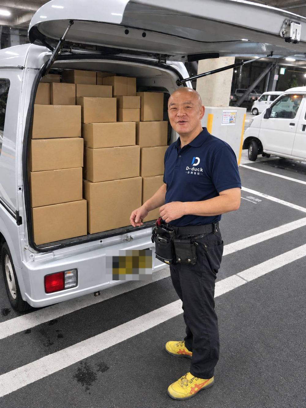 荷物を積み終えて笑うベテランドライバー