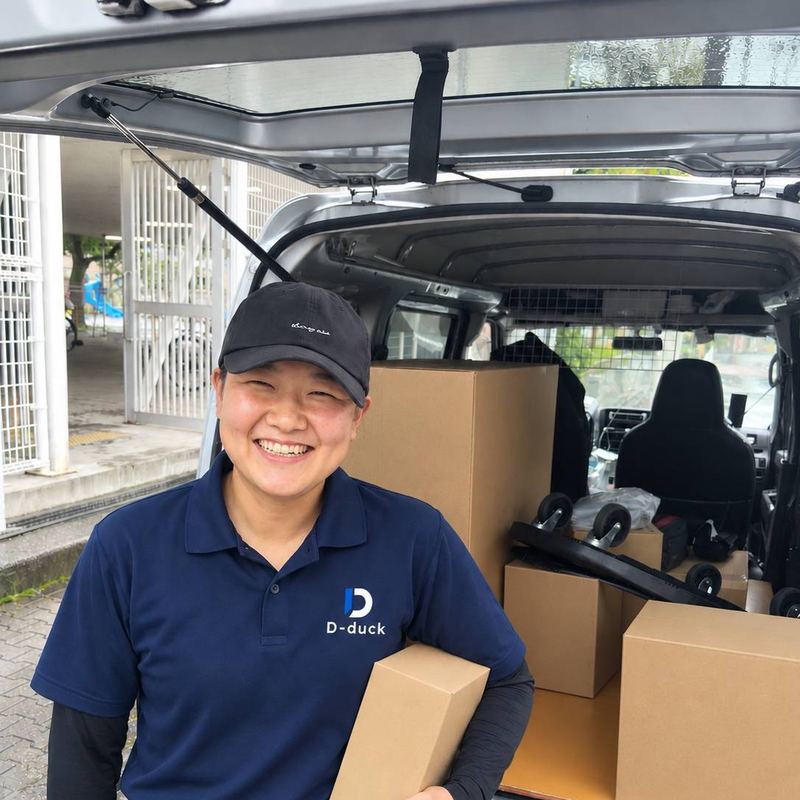 笑顔で荷物を抱える30代女性ドライバー