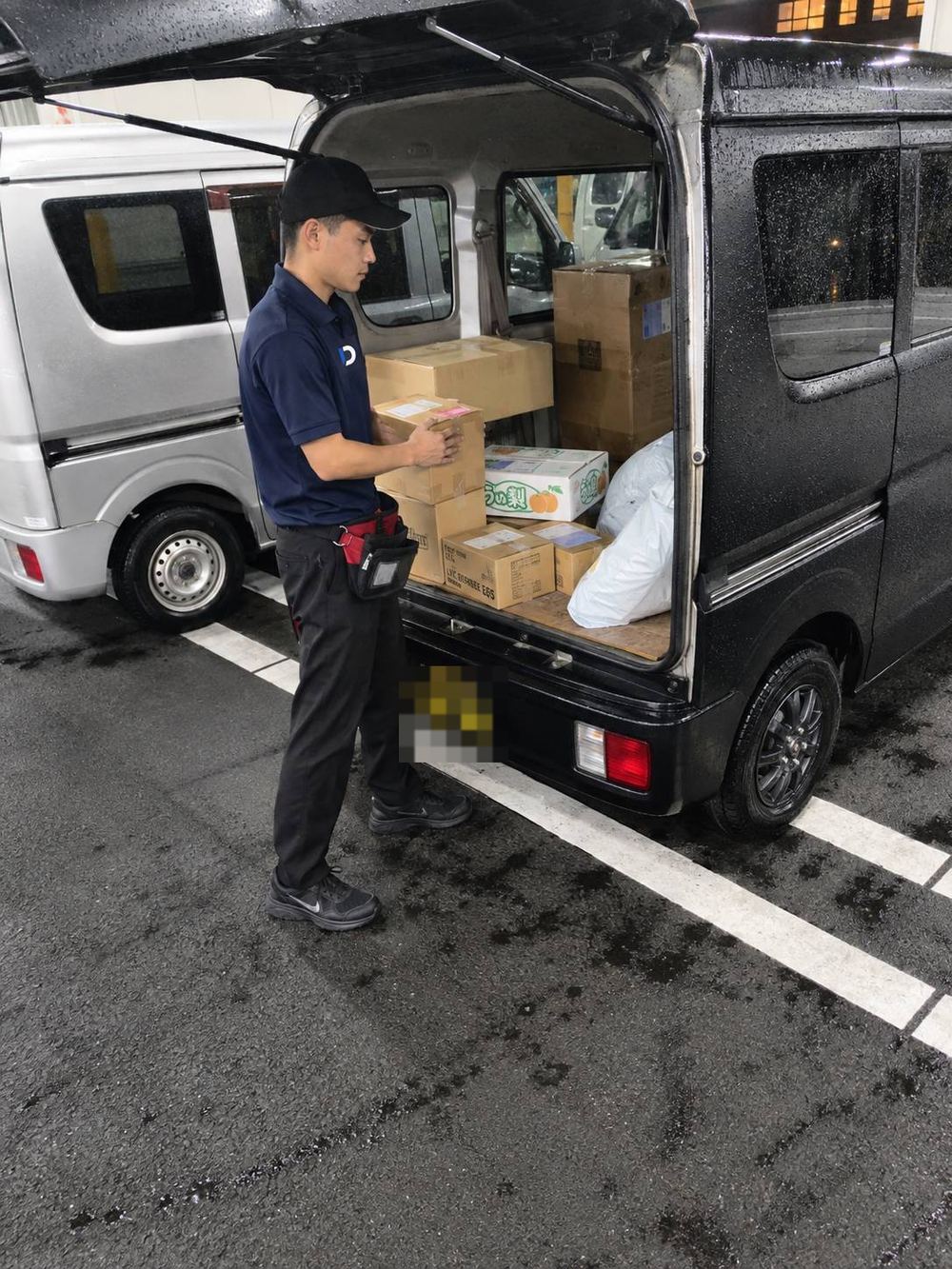 軽バンへ荷物を積み込むドライバー